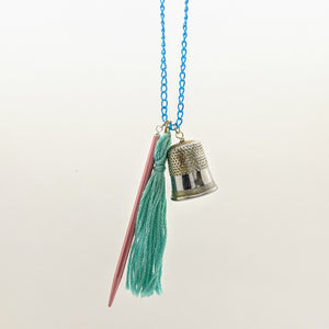 Pink and blue pointed needle, thimble, and tassel knitting needle necklace