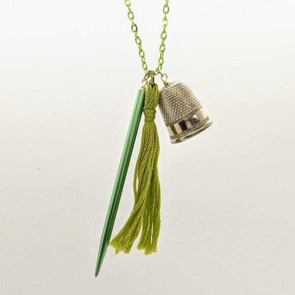 Green pointed needle, thimble, and tassel knitting needle necklace